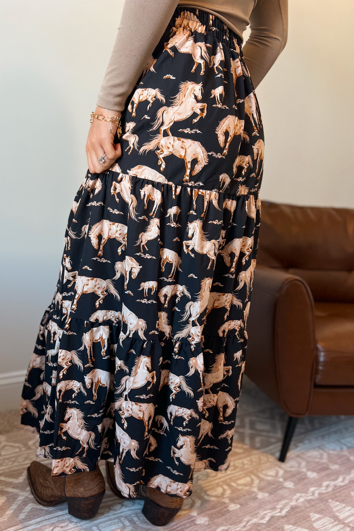 Full-length black midi skirt featuring a repeating horse pattern and tiered design.