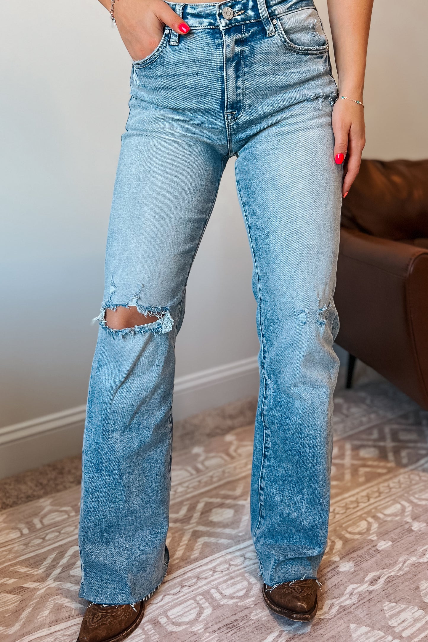Model wearing light wash high-rise straight-leg jeans with subtle distressing at the knee.