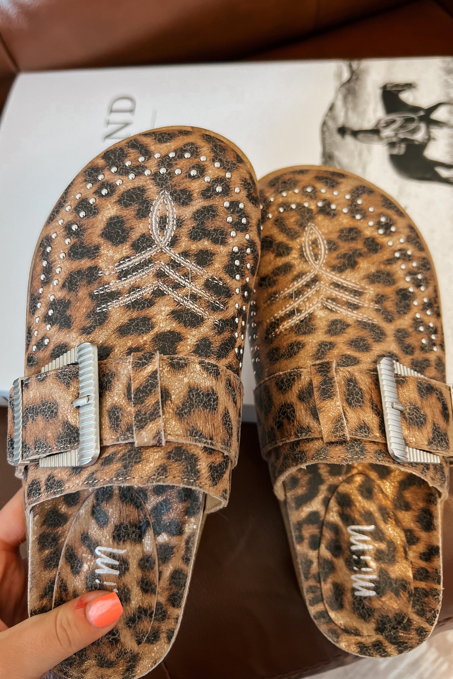 Leopard print mule clogs with silver buckle strap, studded detailing, and closed rounded toe.