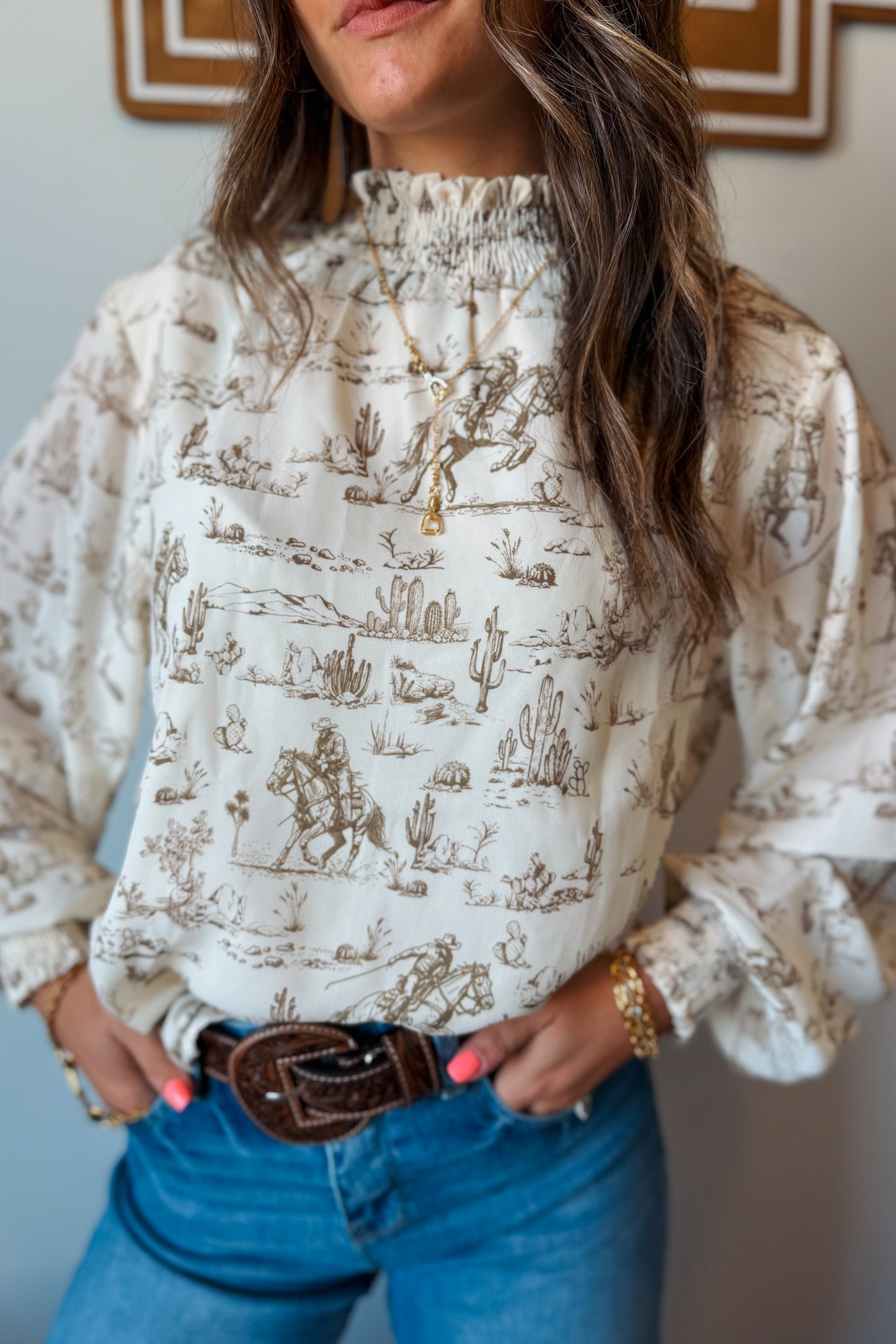 Front view of cream and brown western print long sleeve blouse with ruffle neckline and cuffs.”