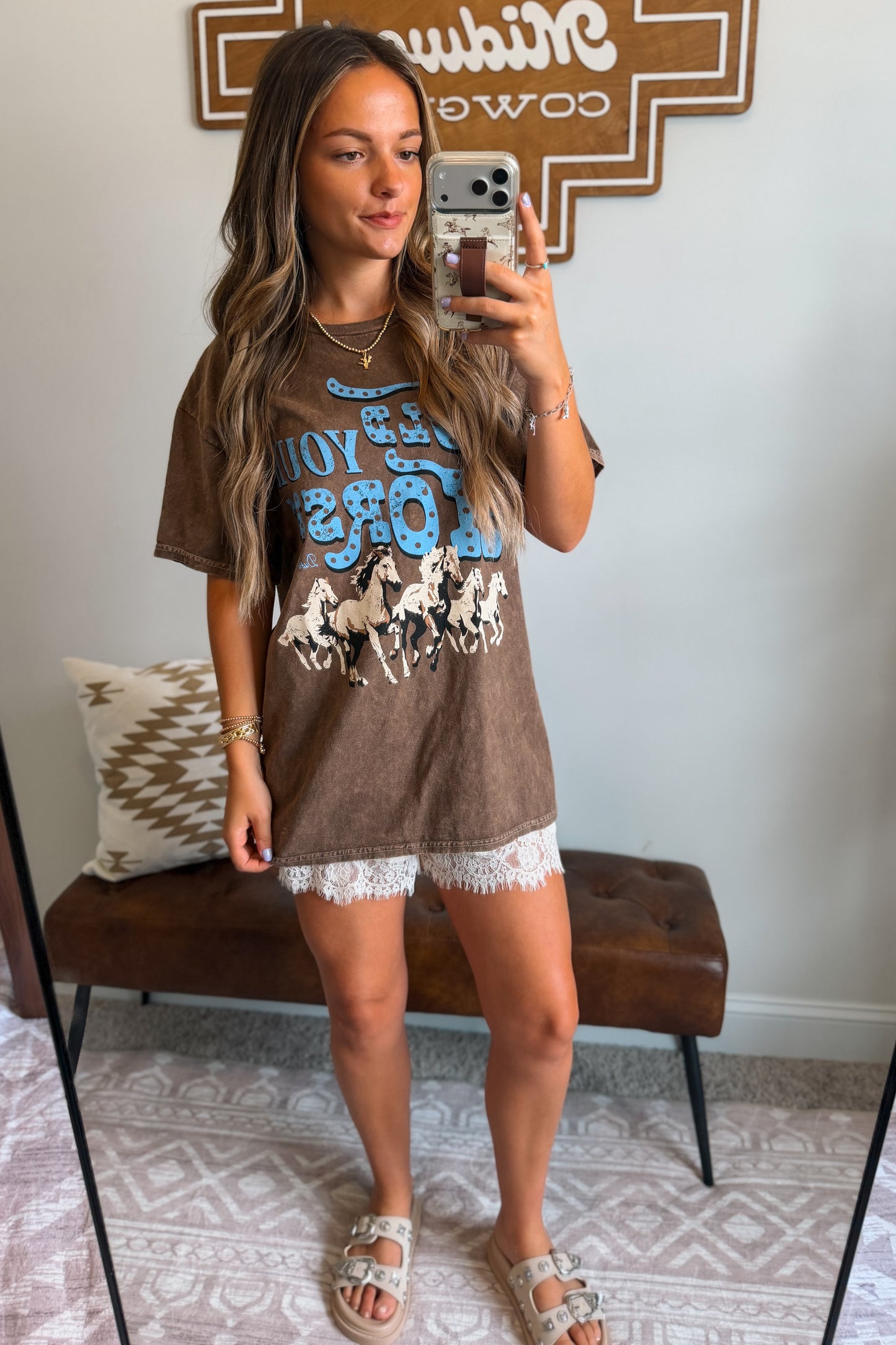 brown graphic tee featuring a "Hold Your Horses" design on the front.