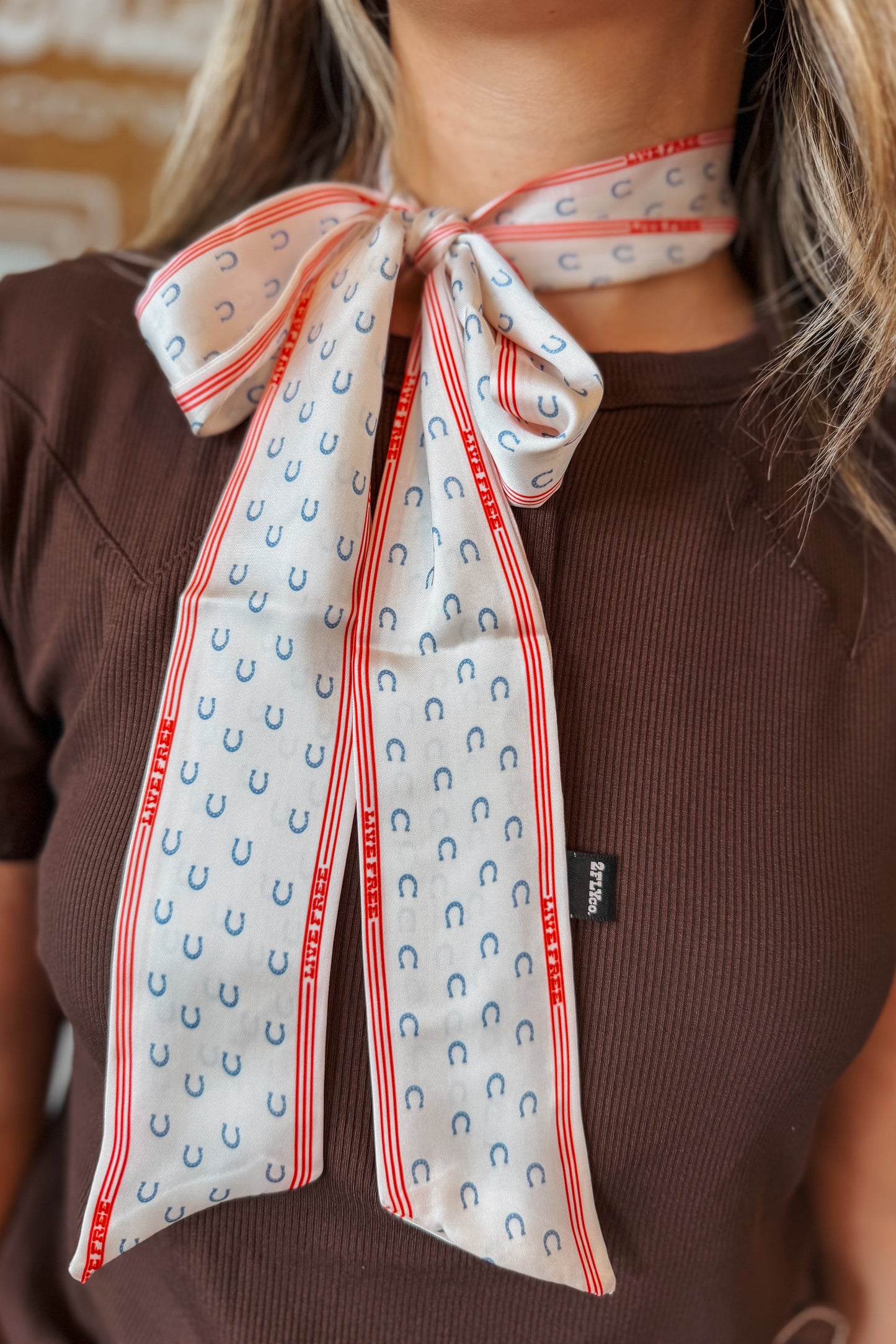 White western twilly scarf featuring blue horseshoe graphics and red accent details. Designed as a narrow decorative scarf that can be styled around the neck, handbag, wrist, or hat.