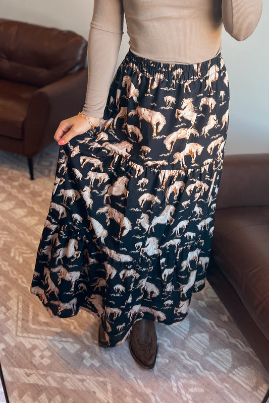 Full-length black midi skirt featuring a repeating horse pattern and tiered design.