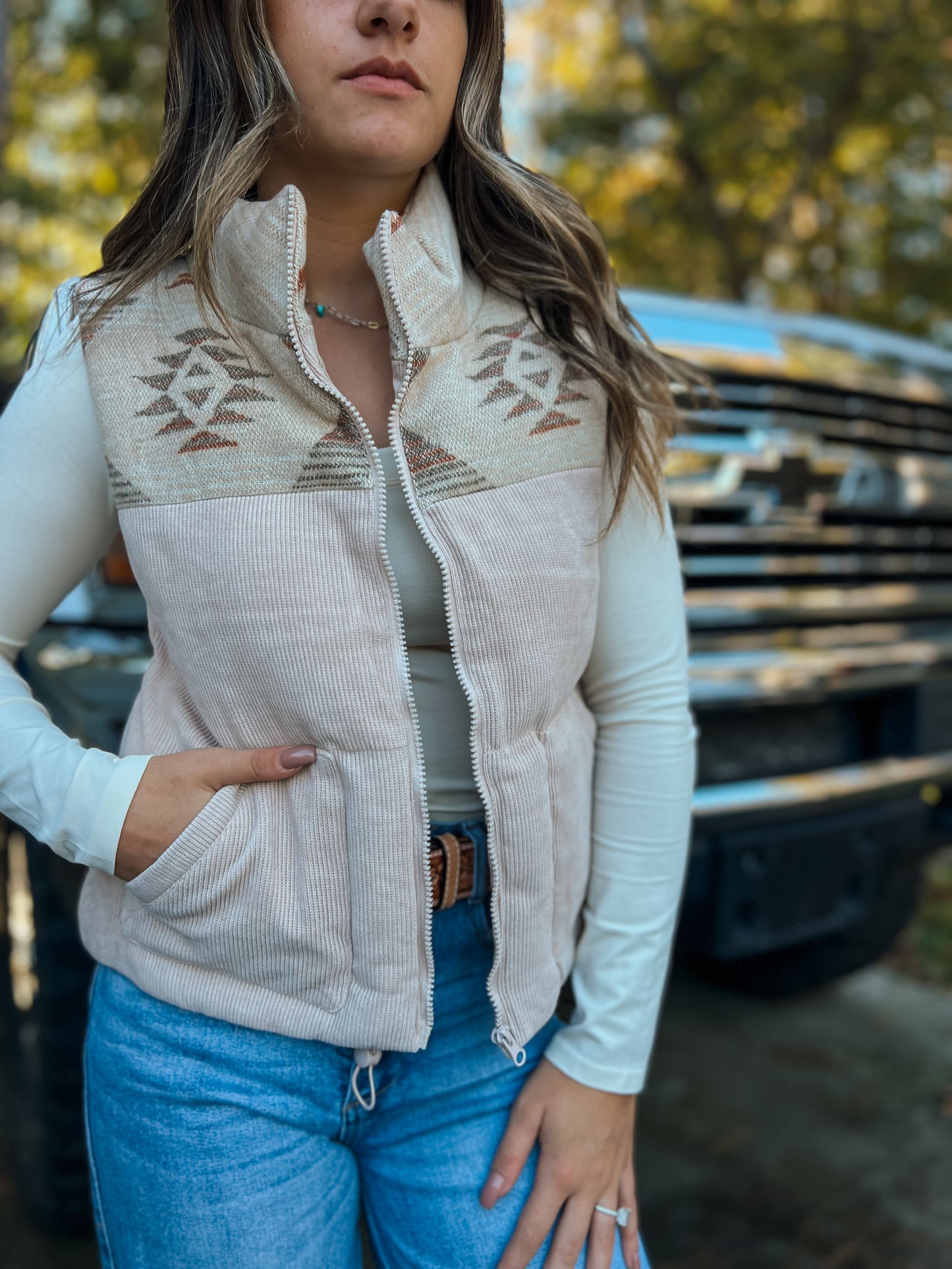Cowgirl layering Aztec graphic vest with jeans and boots