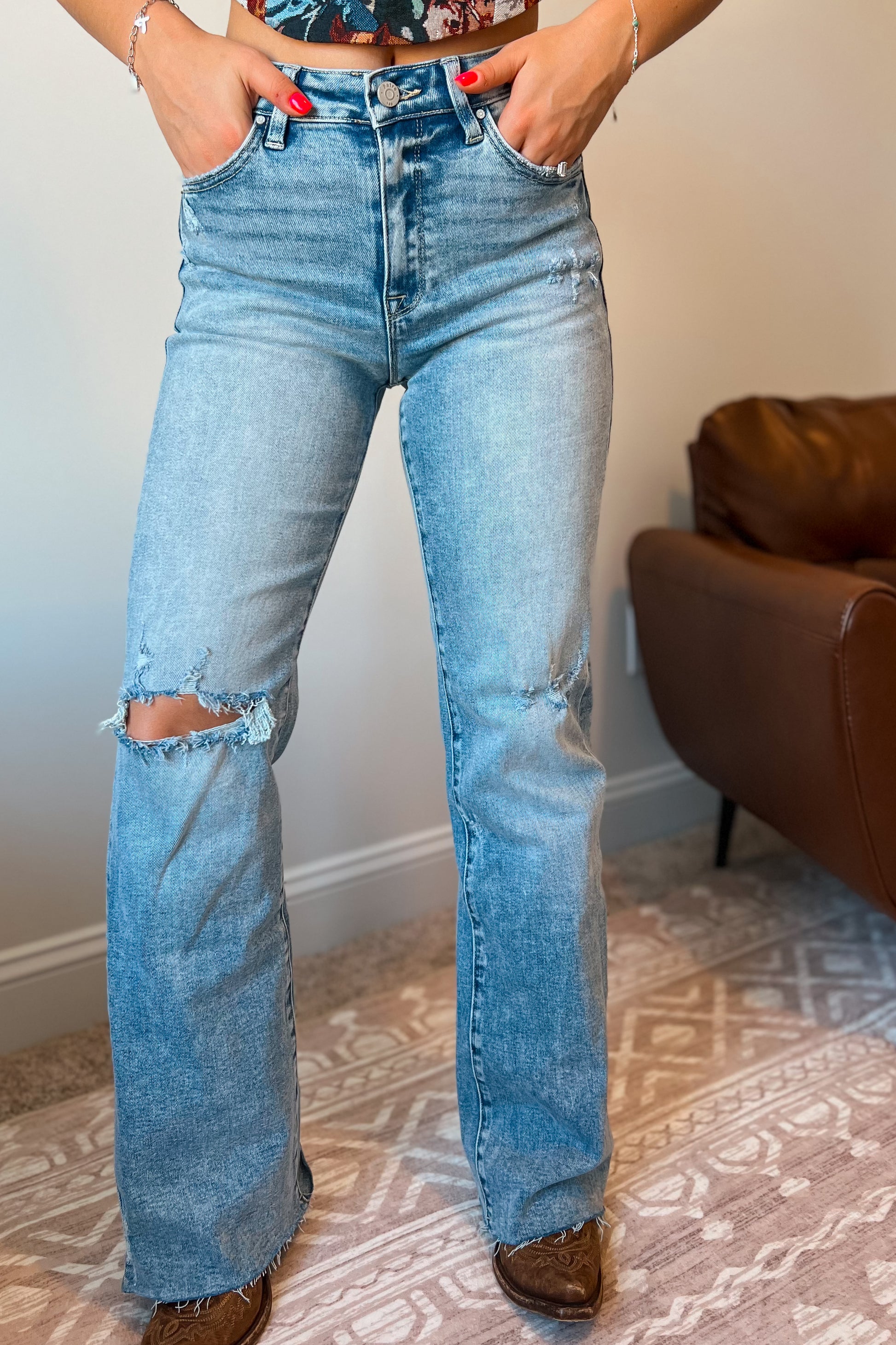 Model wearing light wash high-rise flare-leg jeans with subtle distressing at the knee.