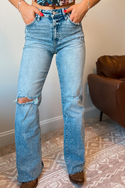 Model wearing light wash high-rise flare-leg jeans with subtle distressing at the knee.