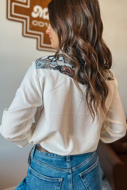 White long sleeve western snap button shirt with contrast southwestern print yoke across the shoulders and matching printed cuffs.