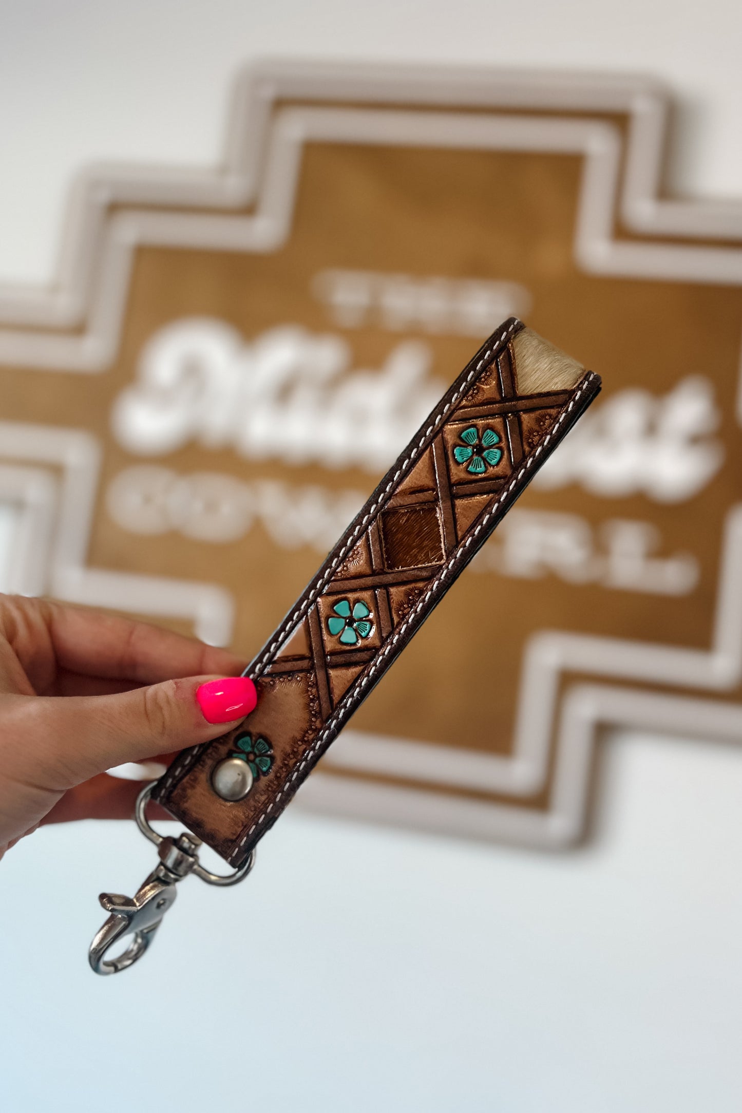 Brown leather wristlet keychain with hair-on cowhide inlay, turquoise accents, contrast stitching, and silver swivel clasp.