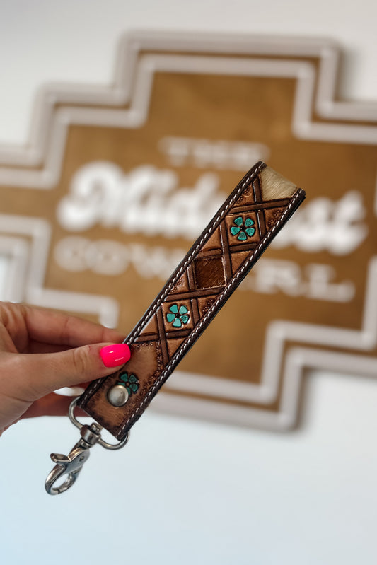 Brown leather wristlet keychain with hair-on cowhide inlay, turquoise accents, contrast stitching, and silver swivel clasp.