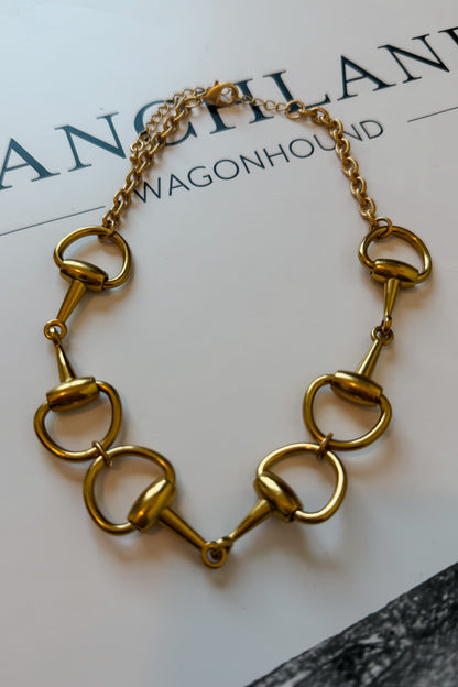 Close-up of gold short necklace featuring a snaffle bit design.