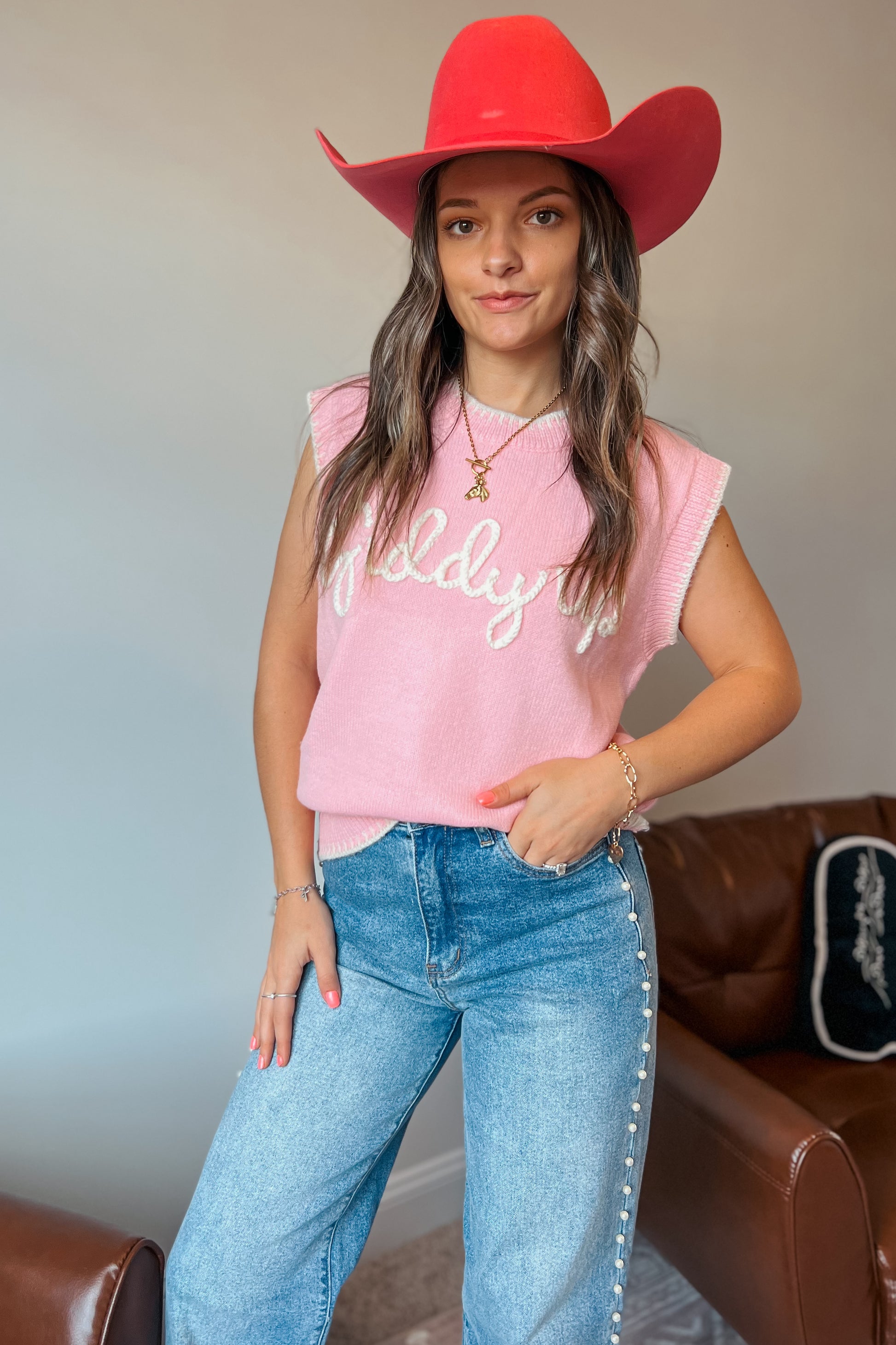 Model wearing pink knit sweater vest with “Giddy Up” text