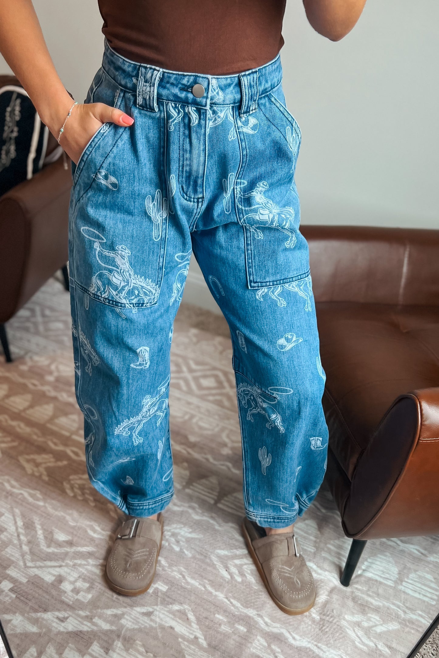 Model wearing western-inspired printed denim jeans with relaxed barrel-leg fit
