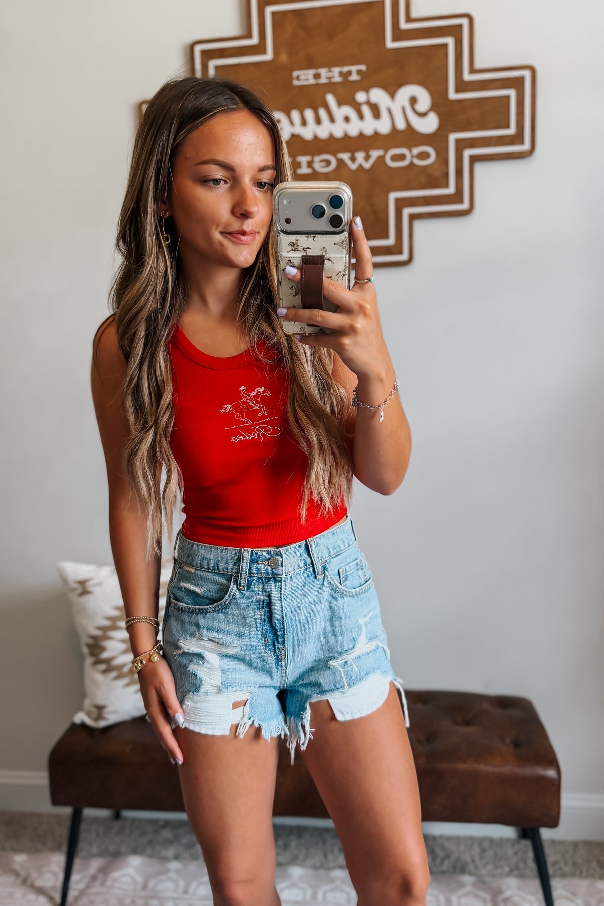 Model wearing high-rise light wash distressed denim cutoff shorts styled with a western-inspired outfit for a casual summer look.