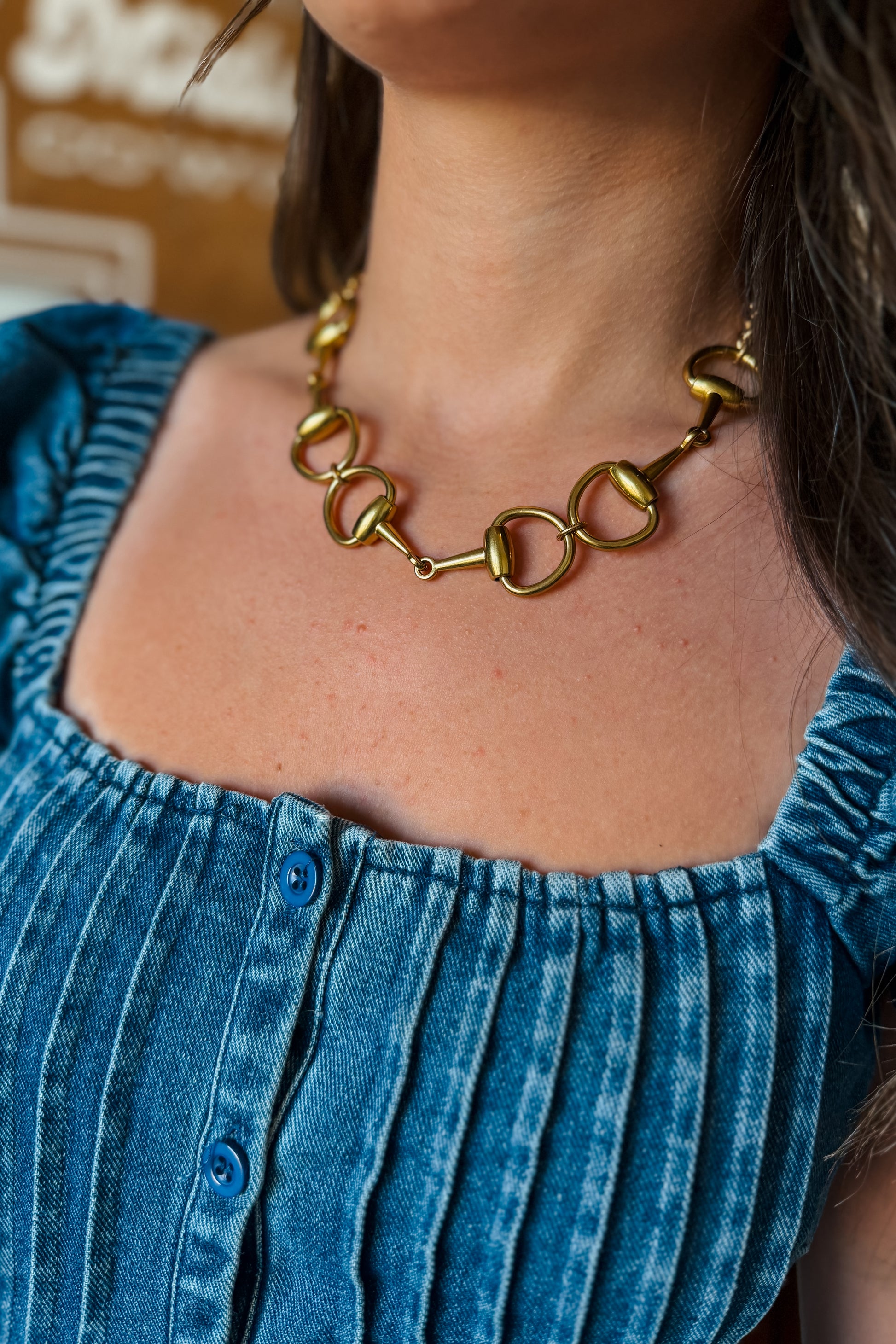 Close-up of gold short necklace featuring a snaffle bit design.