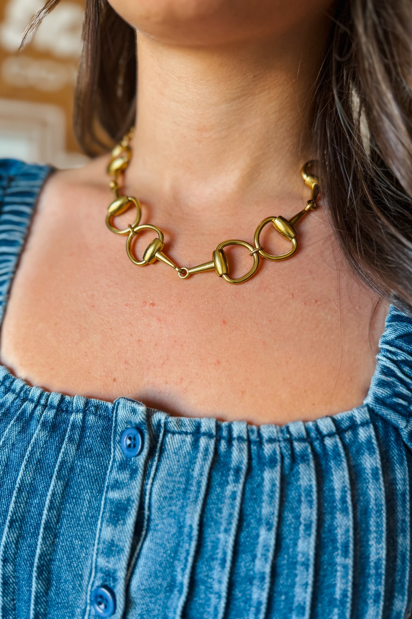 Close-up of gold short necklace featuring a snaffle bit design.