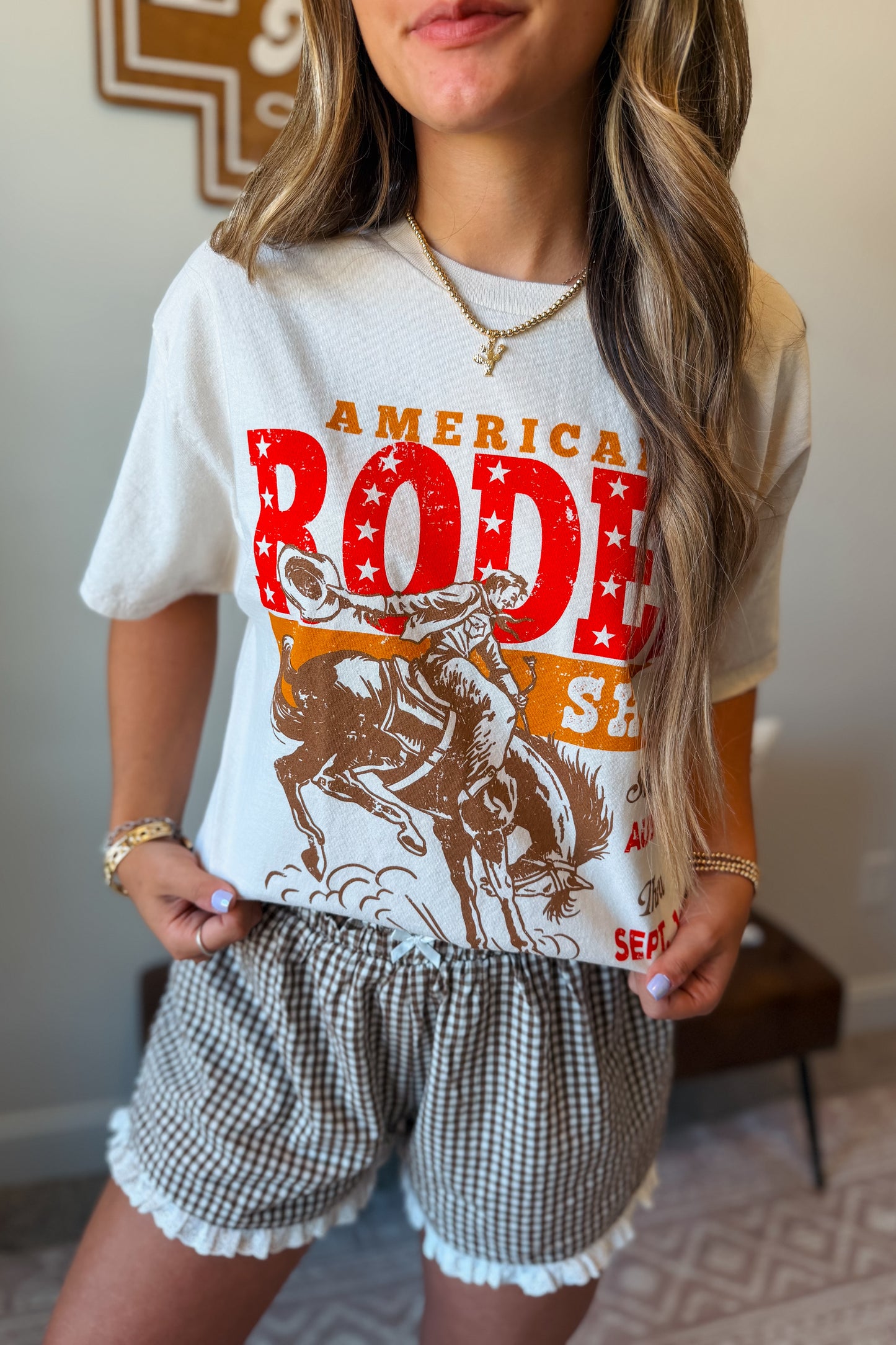 Model wearing a cream oversized American rodeo graphic tee styled with a casual western-inspired outfit.
