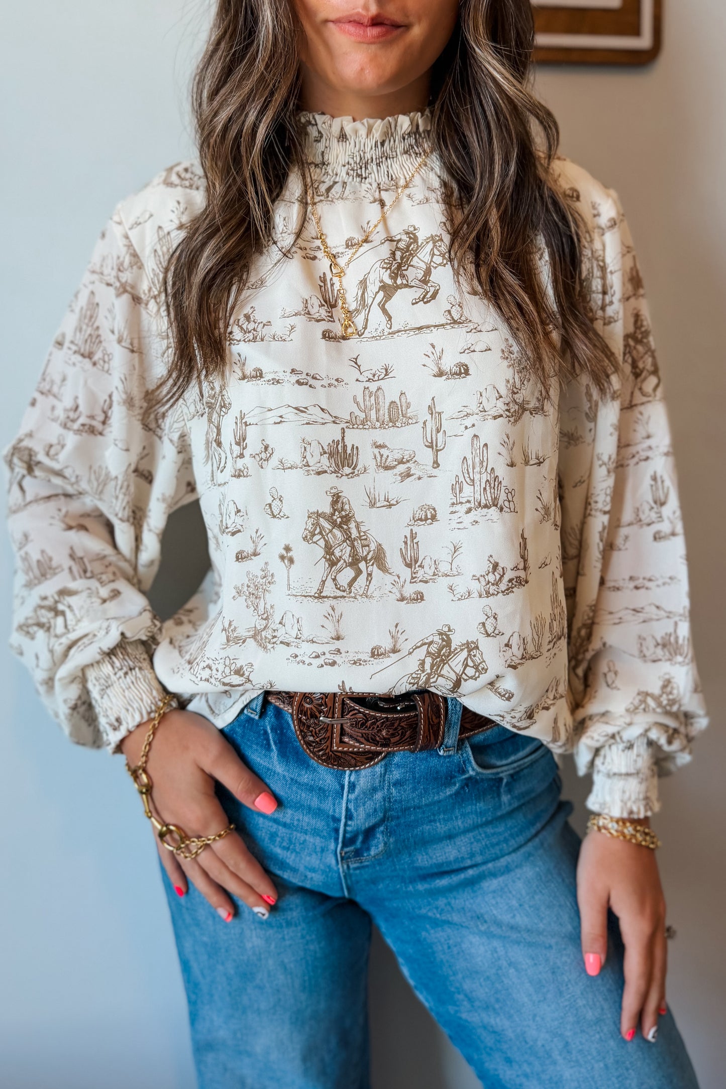 Front view of cream and brown western print long sleeve blouse with ruffle neckline and cuffs.”