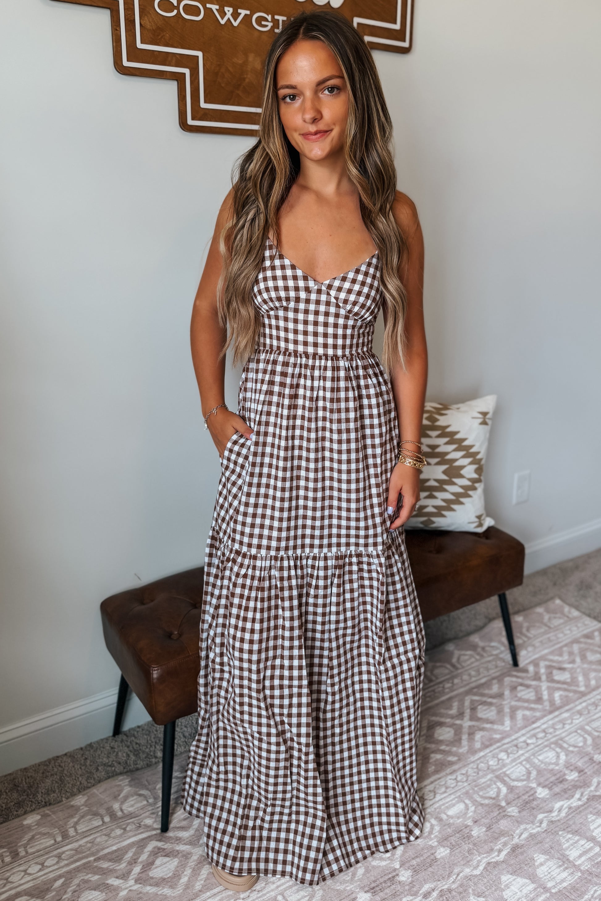 Brown and white gingham maxi dress featuring spaghetti straps, a fitted bodice, and a flowing full-length skirt.