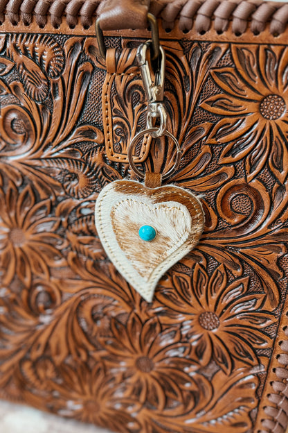 Heart-shaped cowhide keychain with natural brown and white pattern.