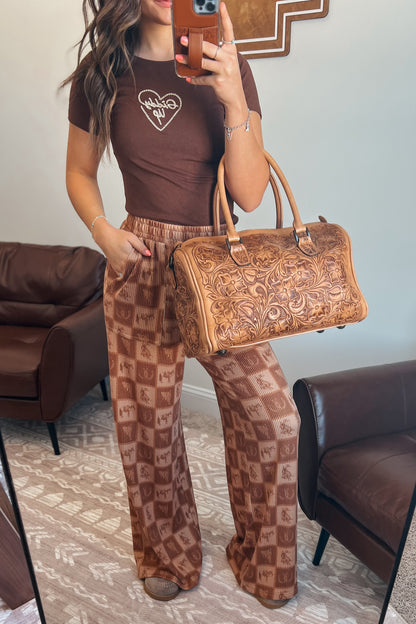 Brown wide-leg ribbed pants with elastic waistband, front pockets, and western checkered print featuring horses and horseshoes.