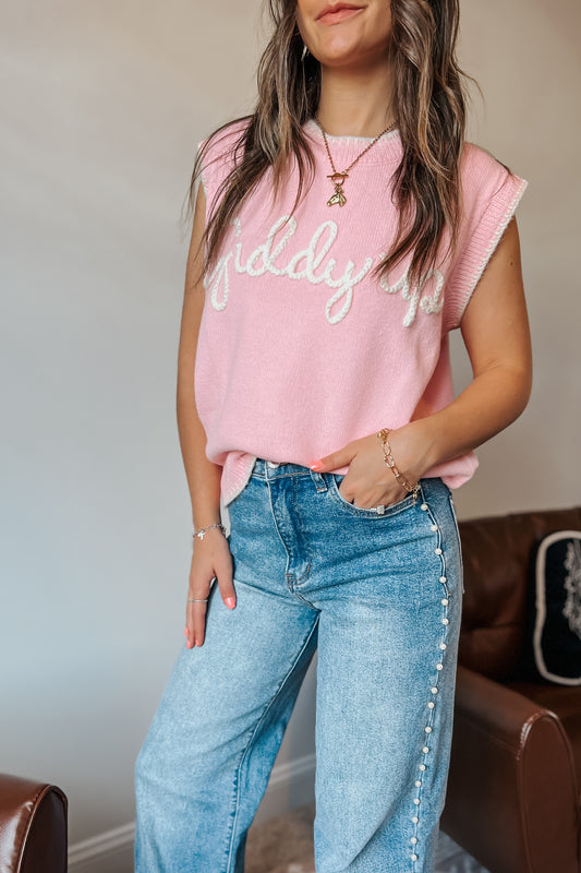 Model wearing pink knit sweater vest with “Giddy Up” text