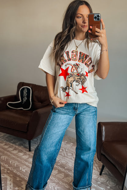 Close-up of oversized western graphic t-shirt featuring “Cowgirl” text, cowboy rider illustration, and red star details
