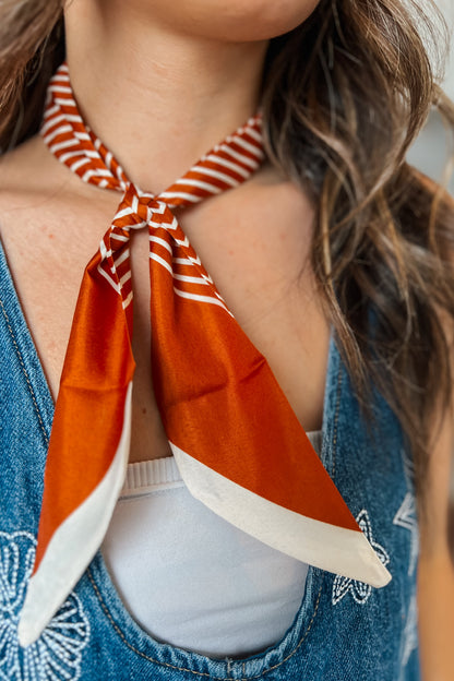 Orange and cream striped Twilly scarf styled tied around the neck 