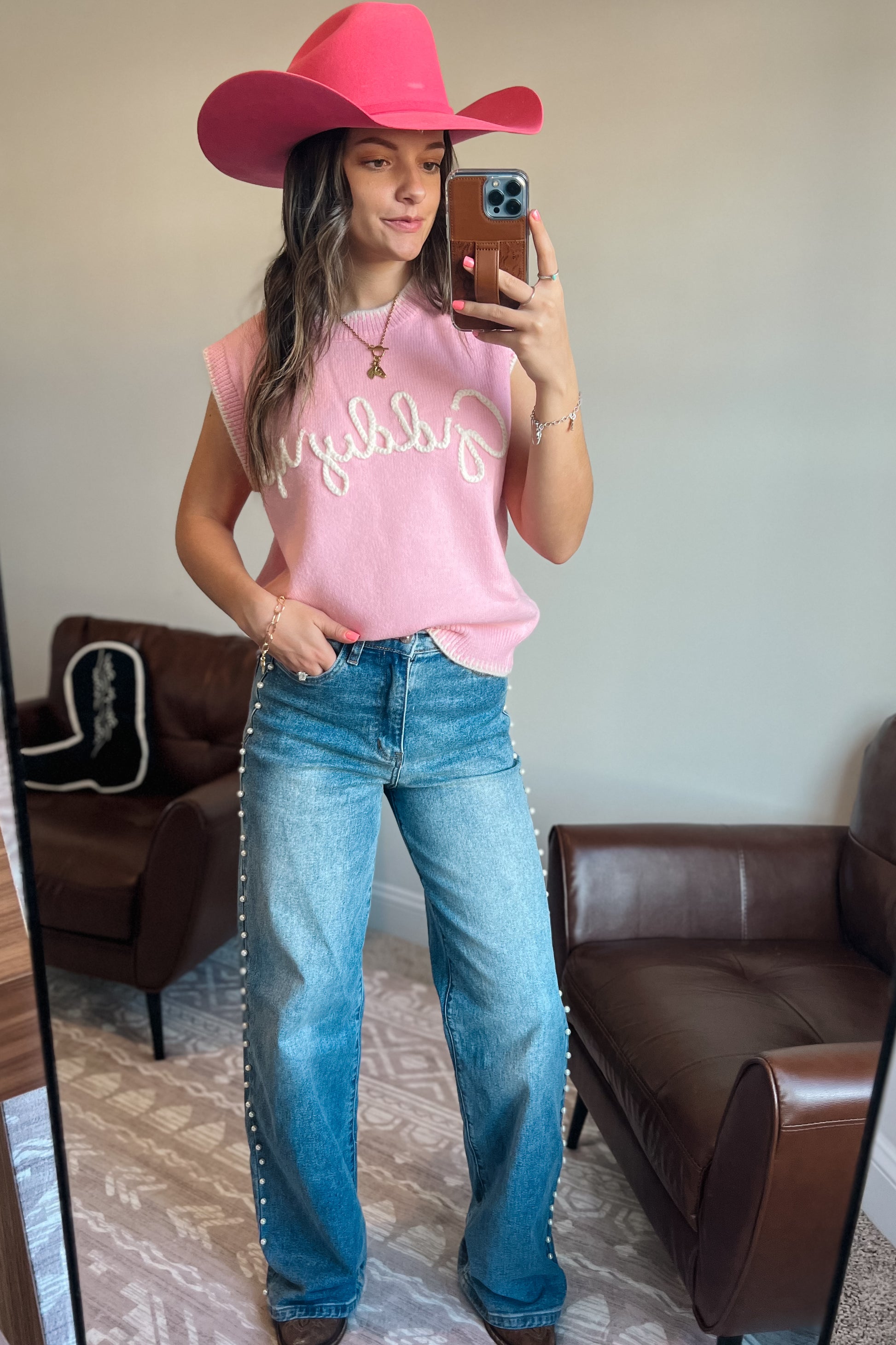 Model wearing pink knit sweater vest with “Giddy Up” text