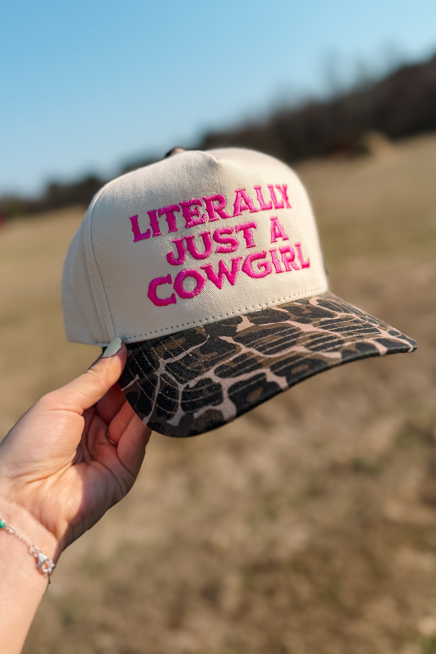 Trucker hat with hot pink “Literally Just a Cowgirl” embroidery and cheetah print brim.