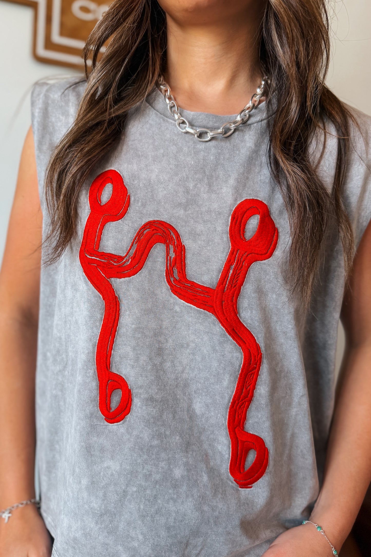 Gray mineral wash muscle tank with red curb bit embroidery.
