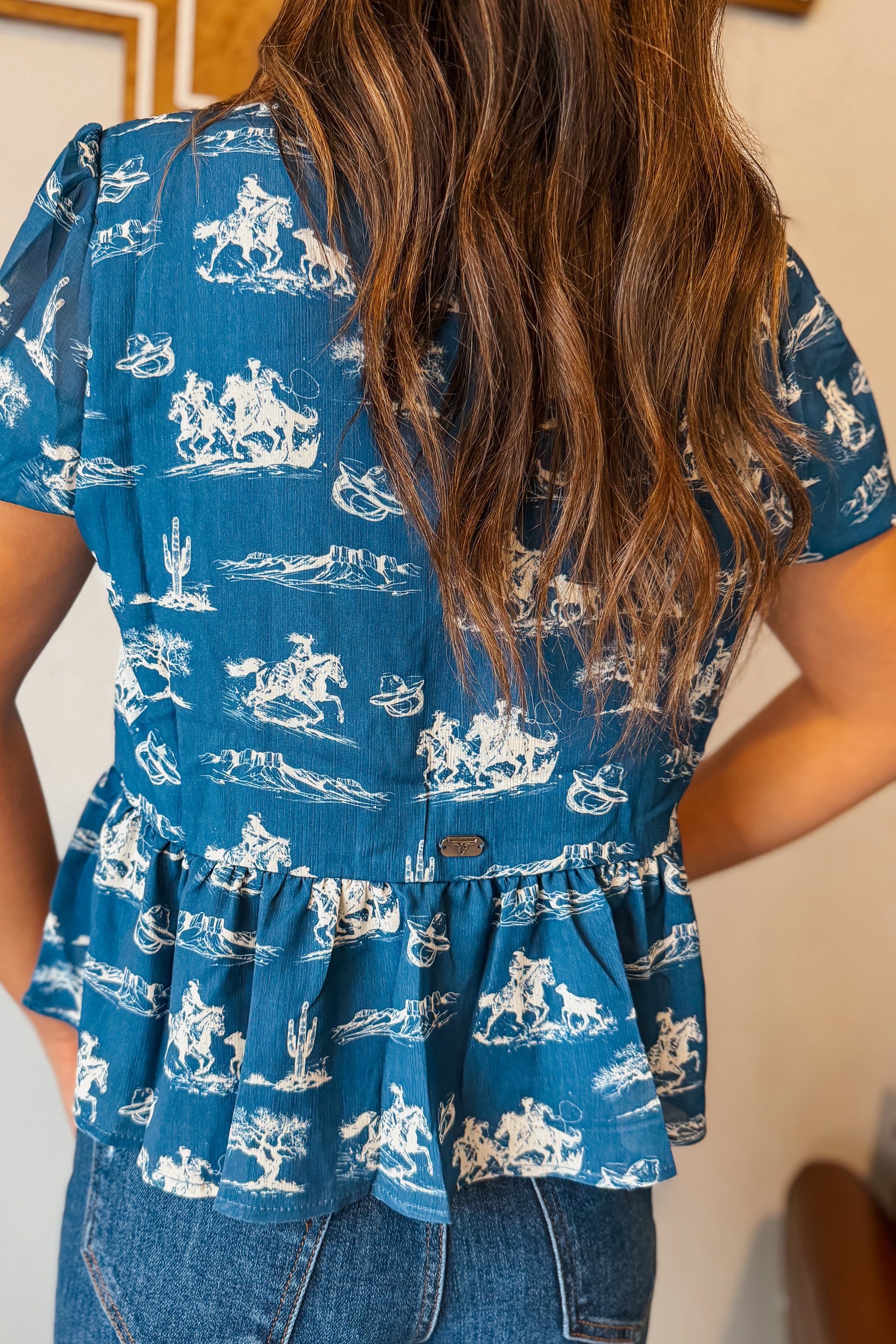 Back view Blue puff sleeve babydoll top with white western print.