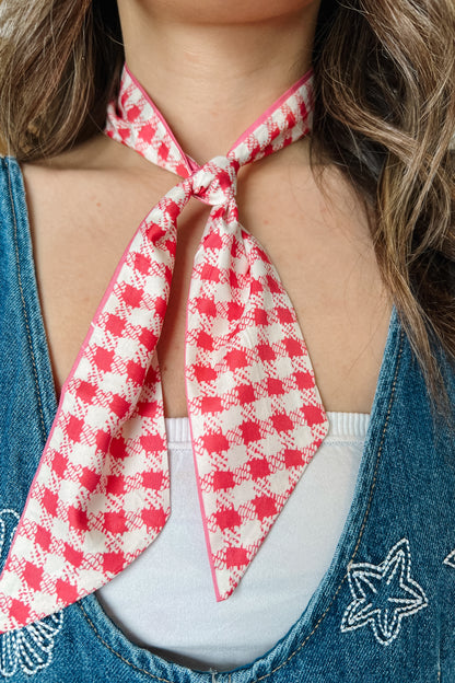 Pink and ivory checkered twilly scarf tied around the neck.
