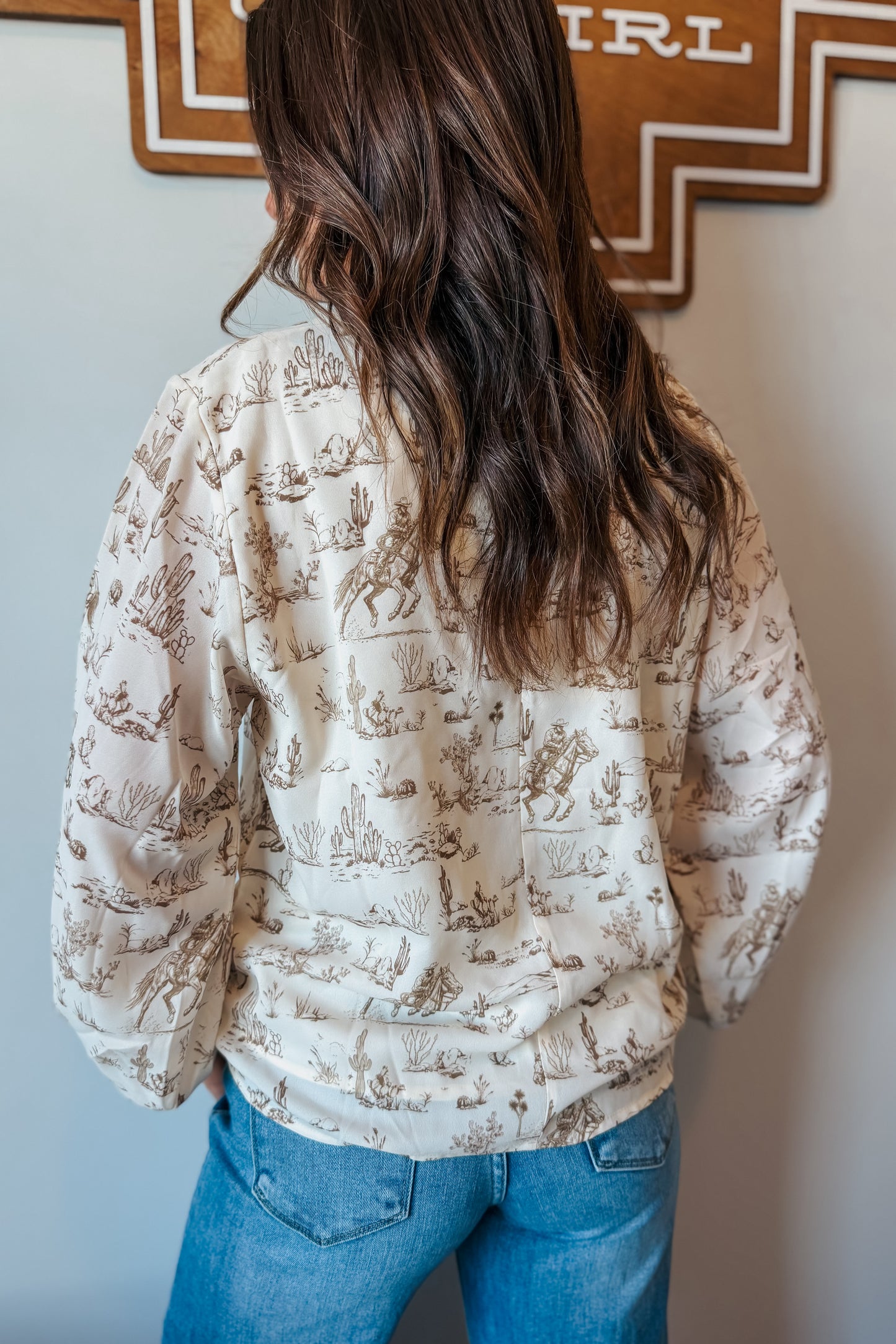 Back view of cream and brown western print long sleeve blouse with long sleeves and relaxed fit.