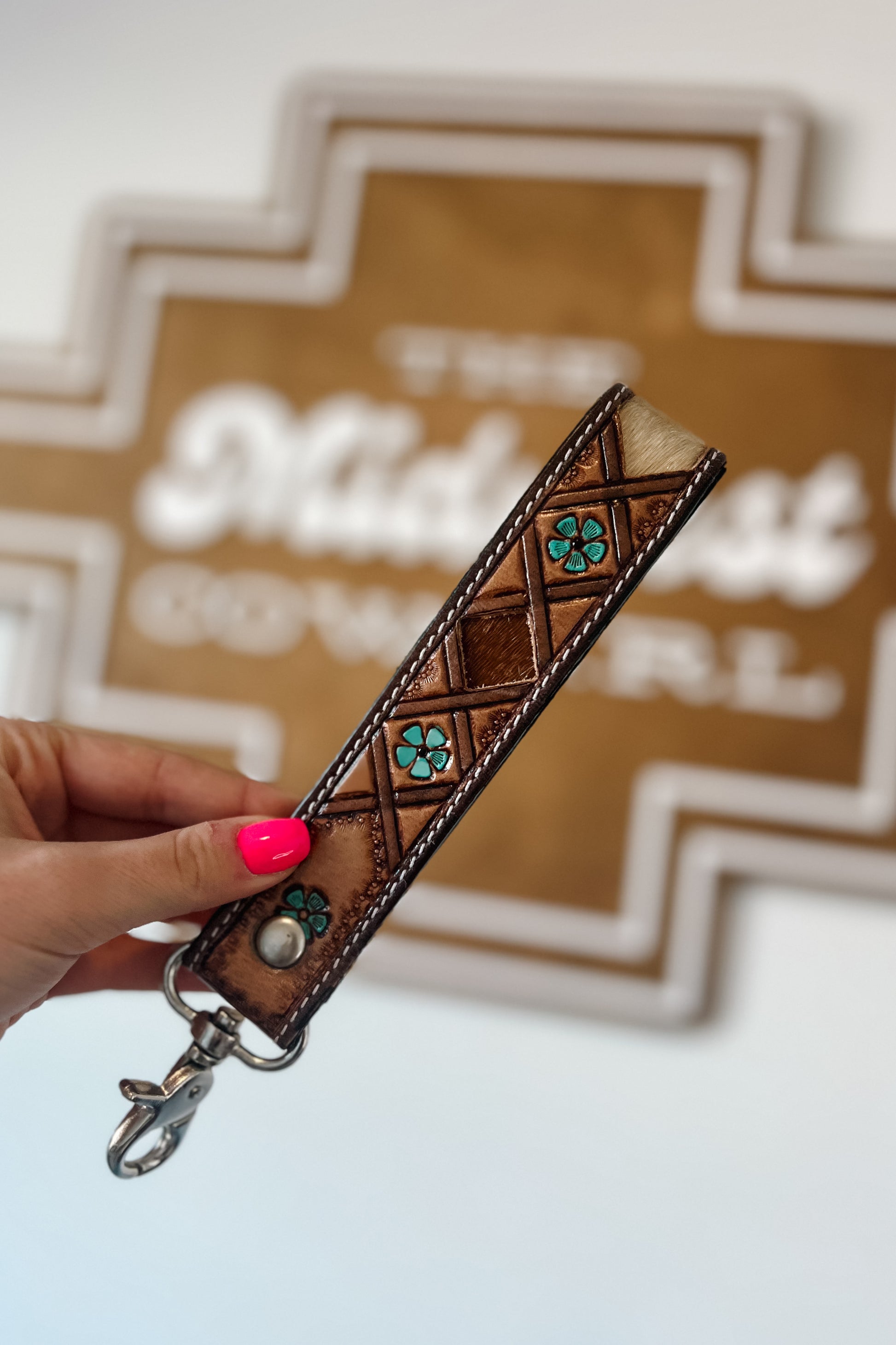 Brown leather wristlet keychain with hair-on cowhide inlay, turquoise accents, contrast stitching, and silver swivel clasp.