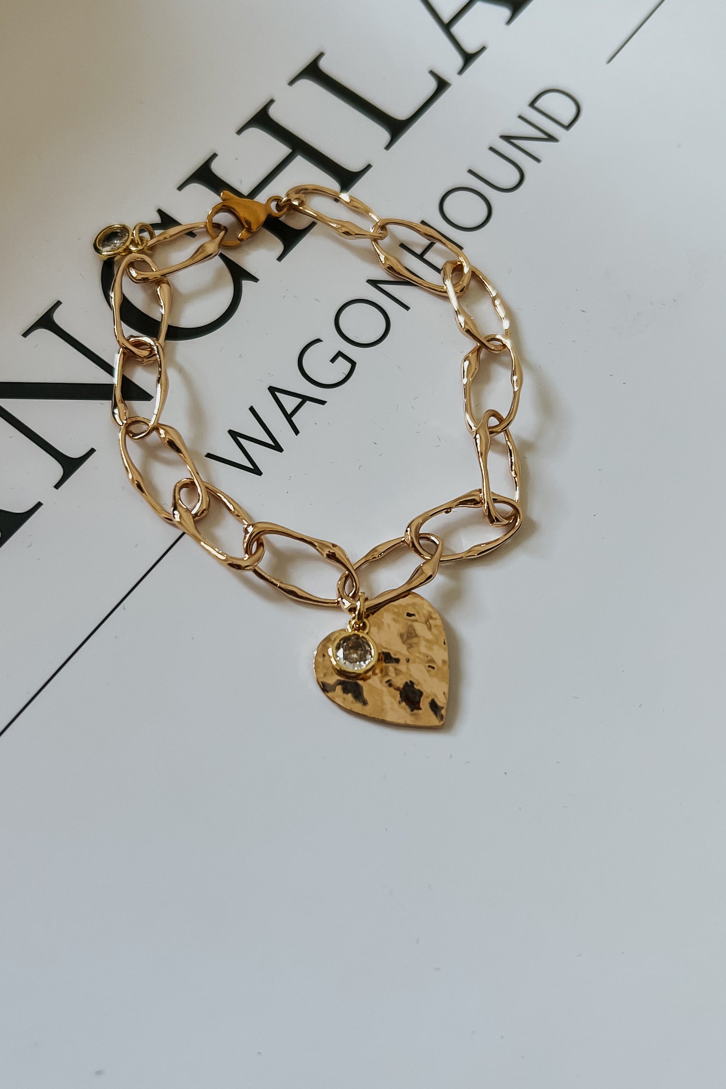 Gold chain bracelet featuring hammered heart charm with crystal detail
