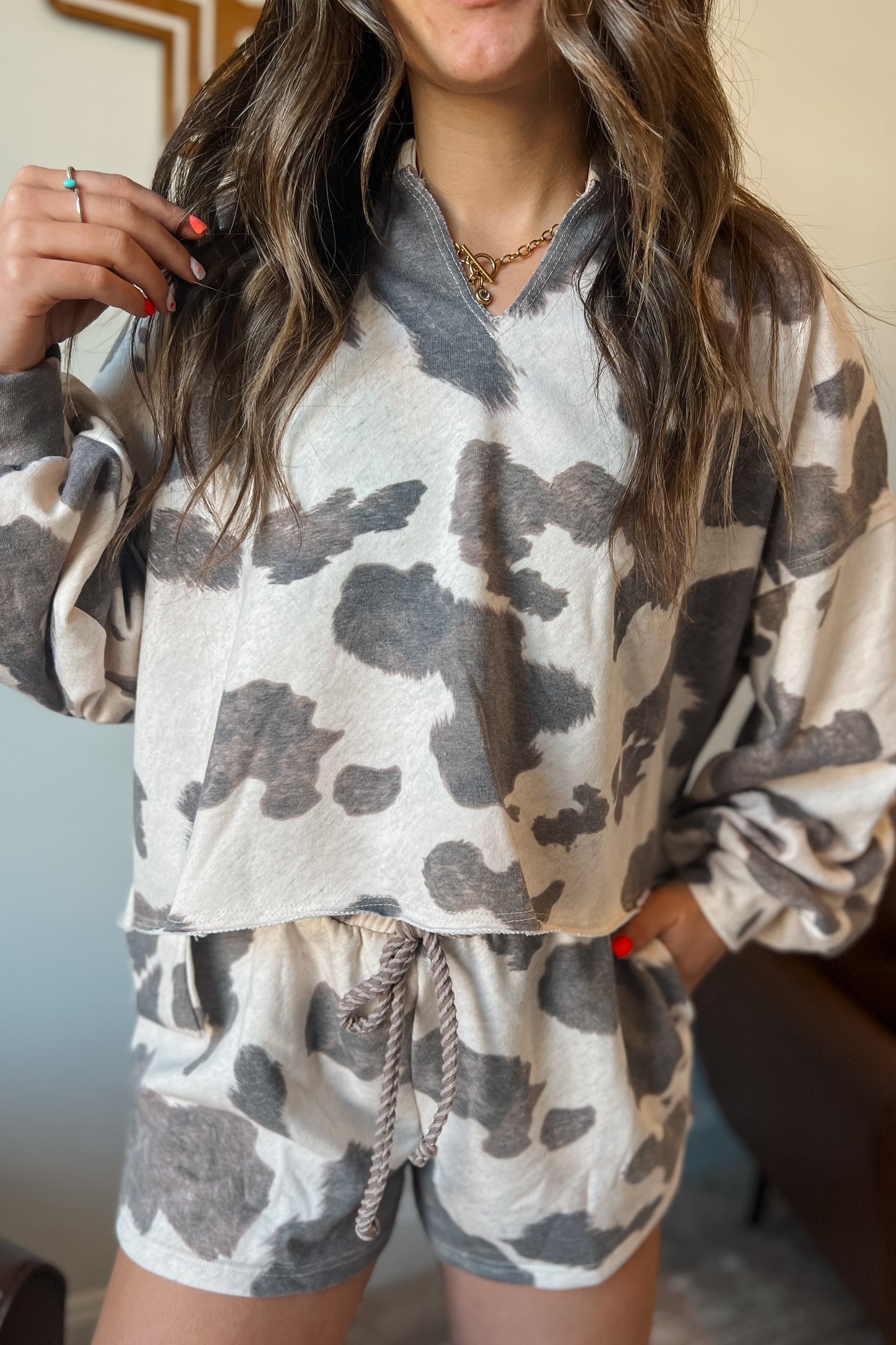 Gray and cream cow print lounge set featuring a long sleeve V-neck top and matching drawstring shorts