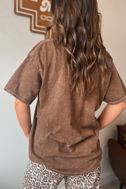Back view of brown vintage-wash short sleeve graphic tee paired with leopard print bottoms.