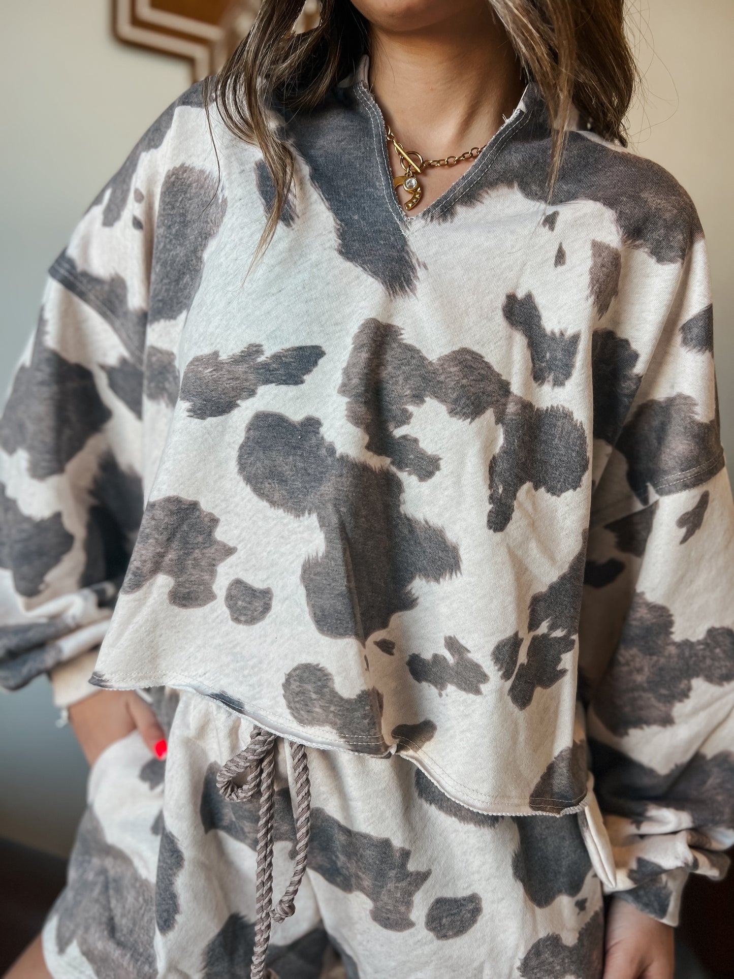 Gray and cream cow print lounge set featuring a long sleeve V-neck top and matching drawstring shorts
