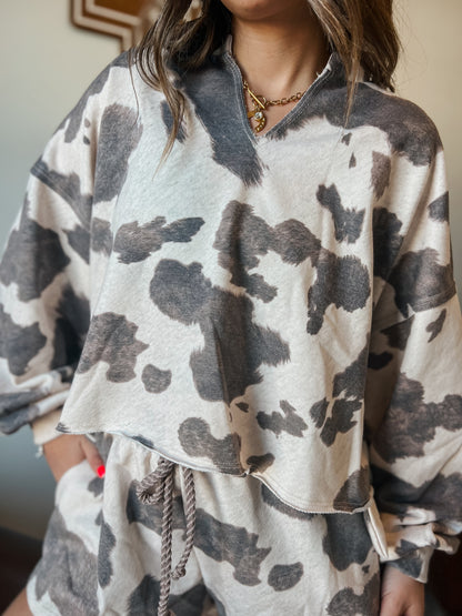 Gray and cream cow print lounge set featuring a long sleeve V-neck top and matching drawstring shorts