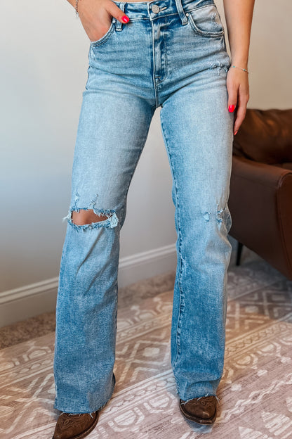 Model wearing light wash high-rise straight-leg jeans with subtle distressing at the knee.