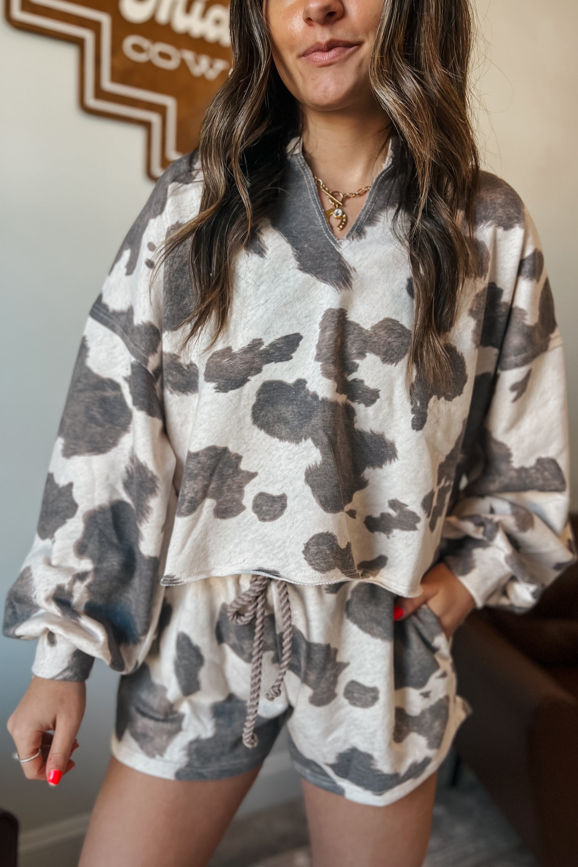 Gray and cream cow print lounge set featuring a long sleeve V-neck top and matching drawstring shorts