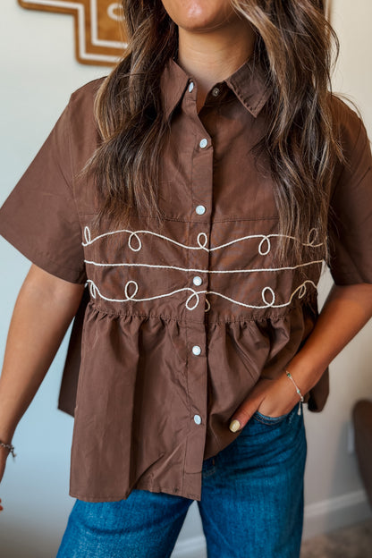 Brown pearl snap babydoll top with embroidered rope detail through the center.