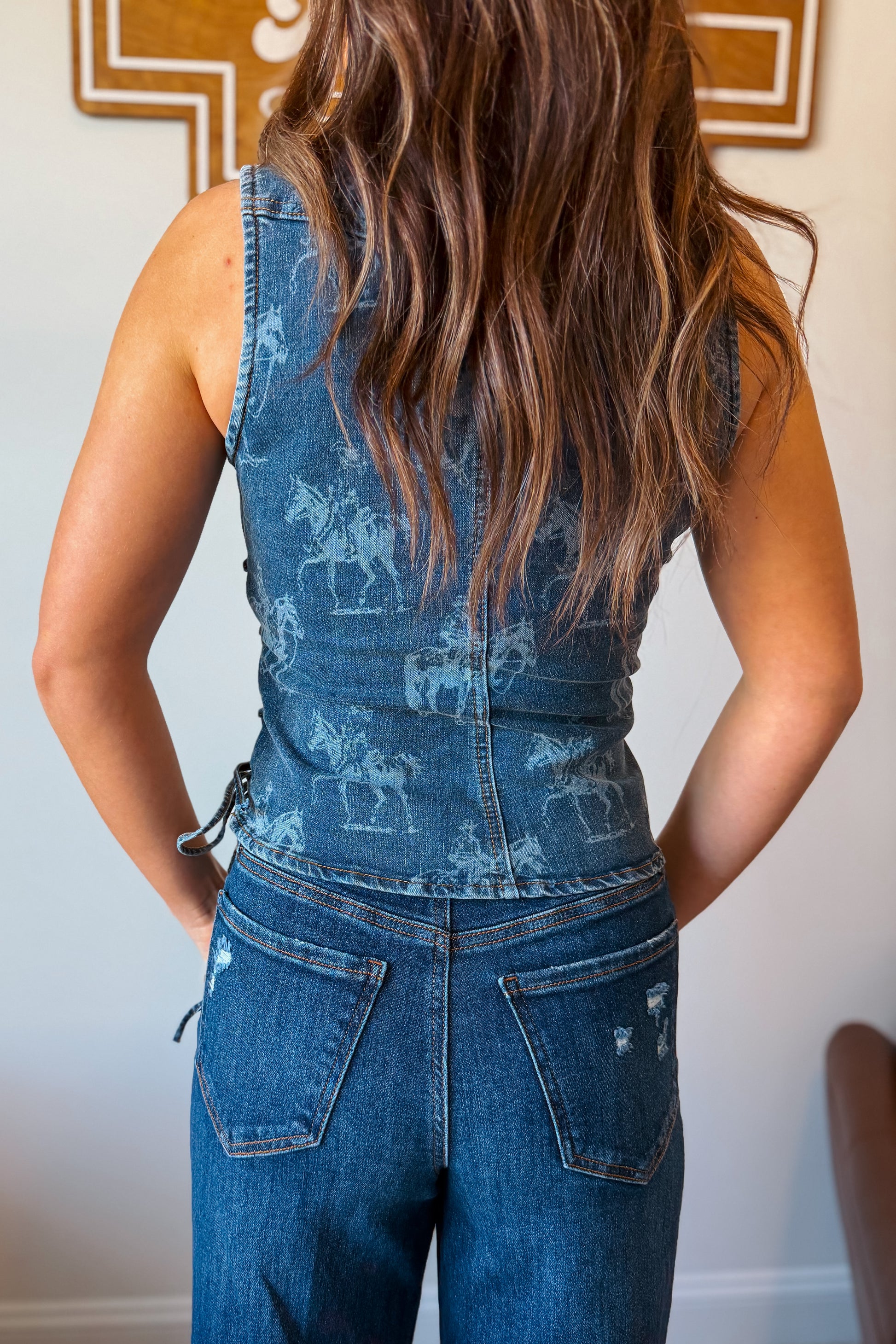 Back view of denim vest with western print detail.