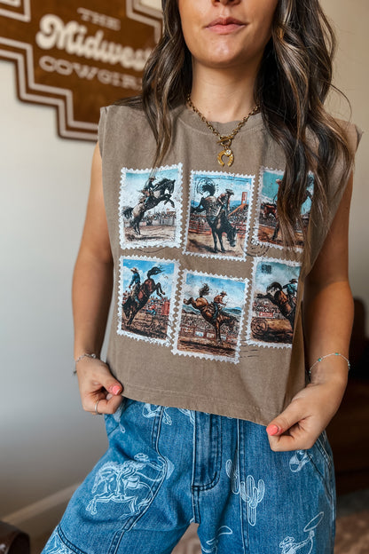 Brown sleeveless muscle tank featuring a vintage rodeo stamp graphic with six cowboy and bronc riding scenes, styled with blue western-print jeans.
