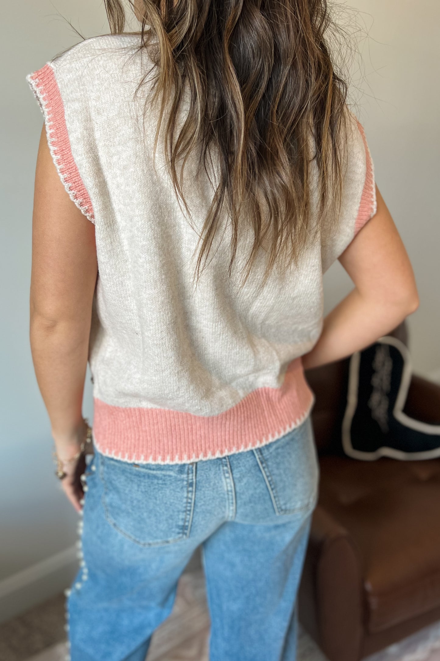 Model wearing western-inspired knit sweater vest with horse design in cream and pink tones
