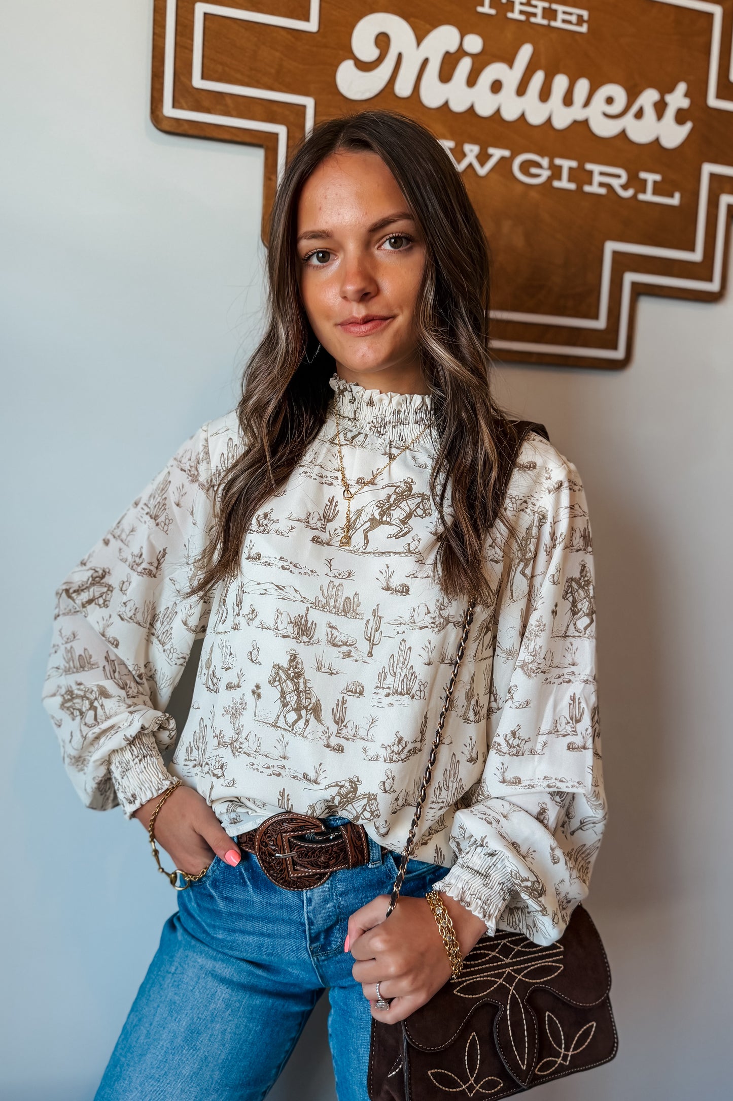 Front view of cream and brown western print long sleeve blouse with ruffle neckline and cuffs.”