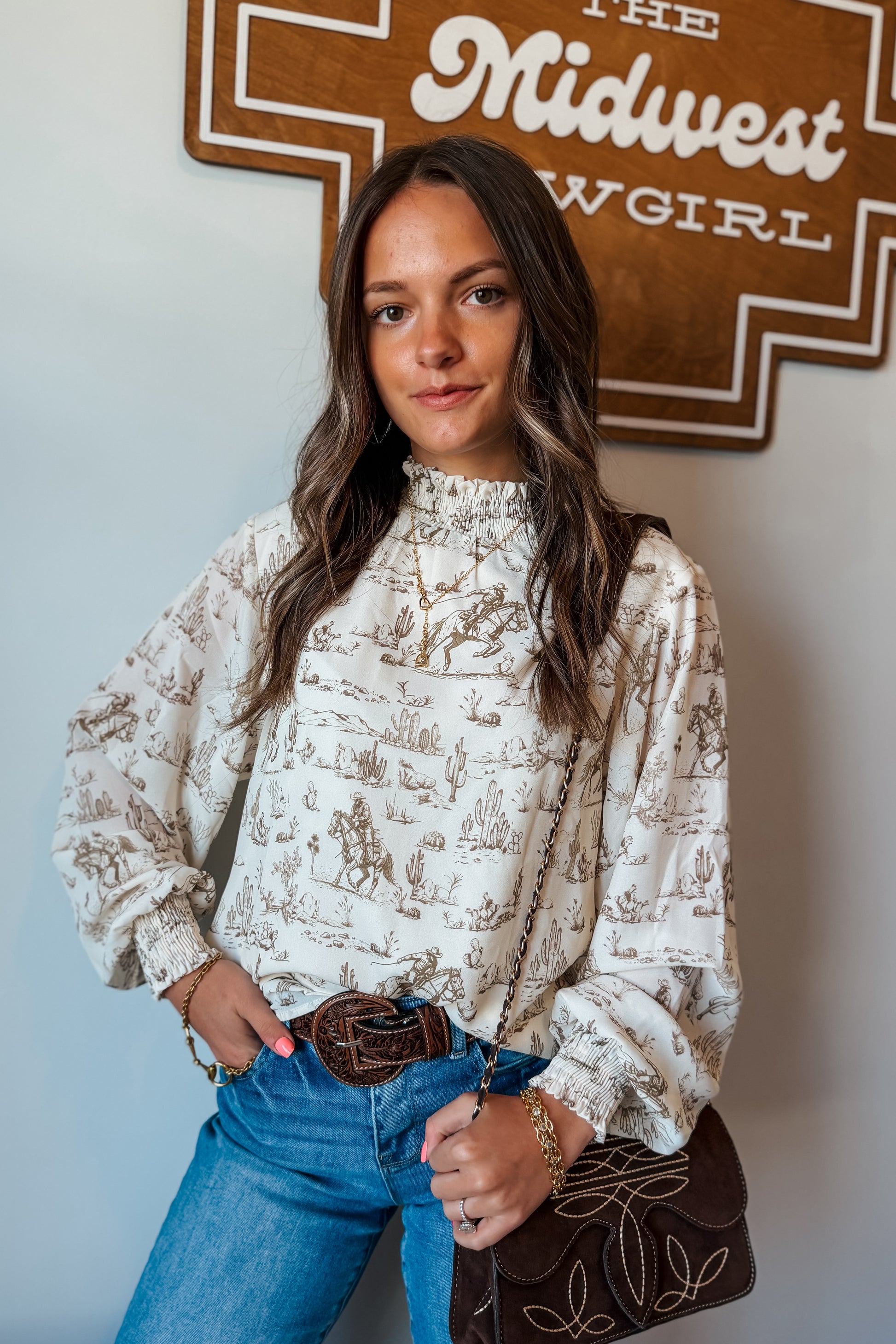 Front view of cream and brown western print long sleeve blouse with ruffle neckline and cuffs.”