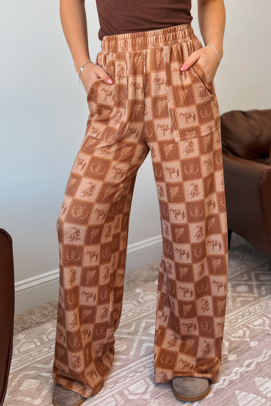 Brown wide-leg ribbed pants with elastic waistband, front pockets, and western checkered print featuring horses and horseshoes.