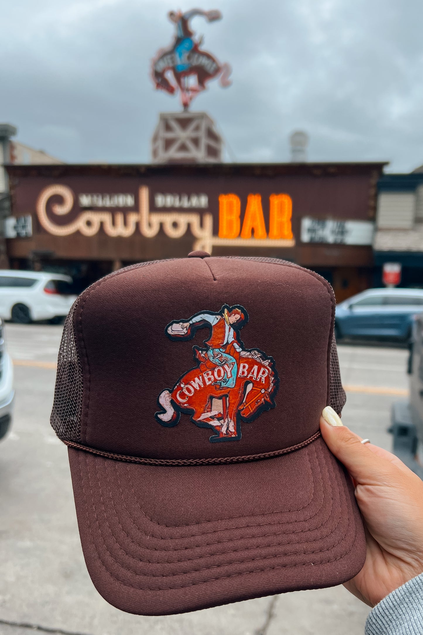 Side view of a brown trucker hat with mesh back panels and a curved brim