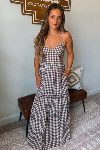 Brown and white gingham maxi dress featuring spaghetti straps, a fitted bodice, and a flowing full-length skirt.